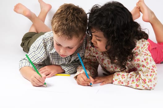 Two friends are drawing together, lying on the floor.