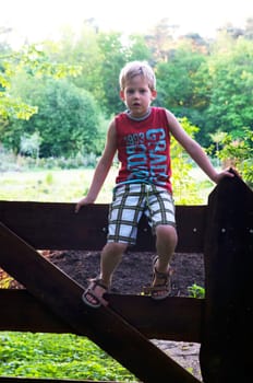 Backlit picture of a boy on a fence.