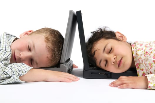 Two kids fallen asleep on their laptops while doing their homework for school.