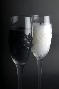 Candles in glasses just blown out, against a black background.