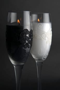 Candles in glasses, against a black background.