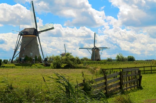 Dutch windmills in a town called Kinderdijk against a blue sky with clouds.