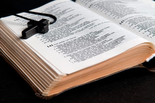Closeup of Dutch Bible with cross, on black background.