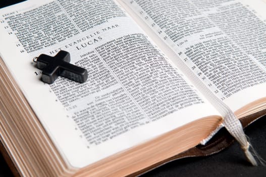 Closeup of Dutch Bible with cross, on black background.
