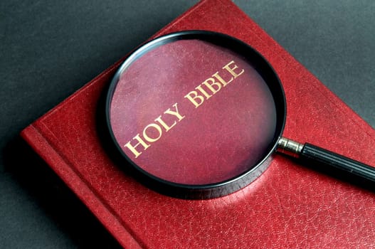 Loupe on a Bible. If  you're searching for answers, read it!