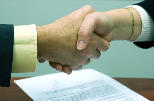 Shaking hands above a signed contract.