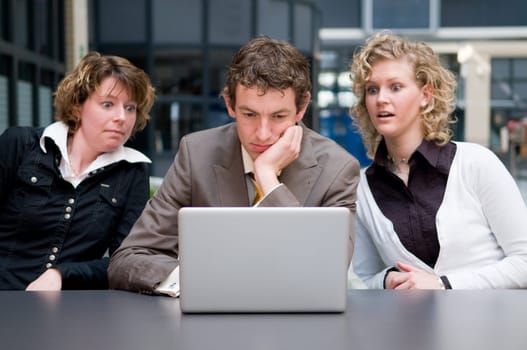 Two businesswoman are shocked by what their male colleague is doing on his laptop...