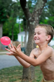 Young boy playing a game with water filled balloons. Don't let it splash in your hands....