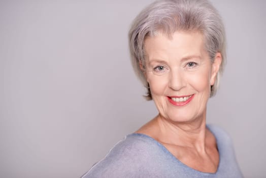 Studio recording of an active senior woman against a grey background