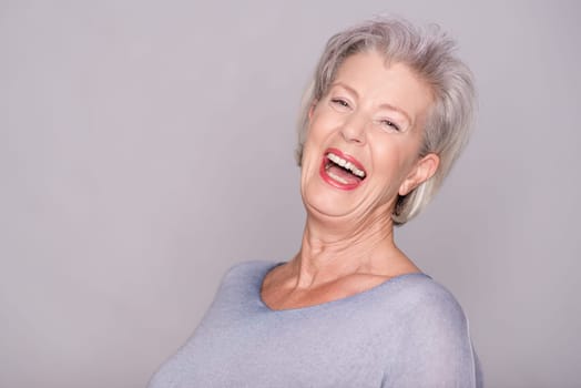 Studio recording of an active senior woman against a grey background
