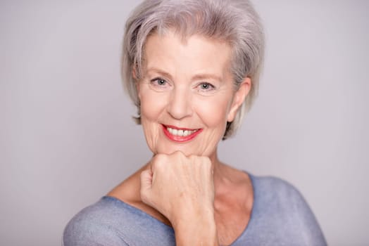 Studio recording of an active senior woman against a grey background