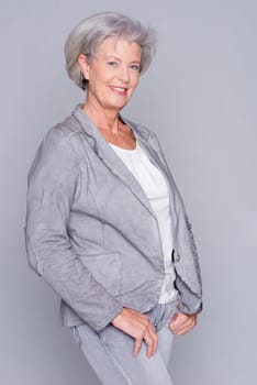 Studio recording of an active senior woman against a grey background