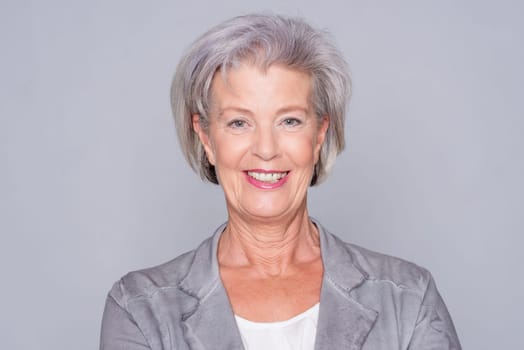 Studio recording of an active senior woman against a grey background