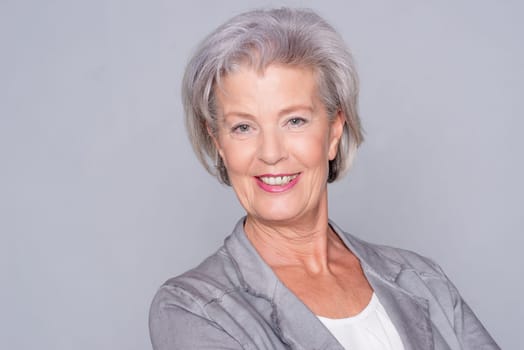 Studio recording of an active senior woman against a grey background