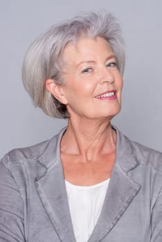 Studio recording of an active senior woman against a grey background