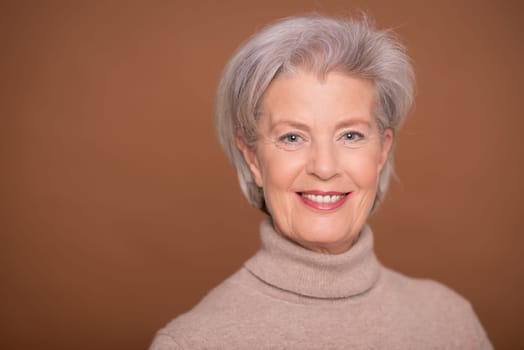 Studio recording of a smiling older woman against a brown background