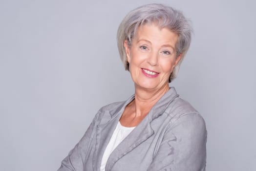 Studio recording of an active senior woman against a grey background