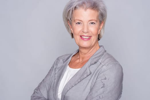 Studio recording of an active senior woman against a grey background
