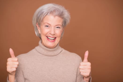 Studio recording of a smiling older woman against a brown background