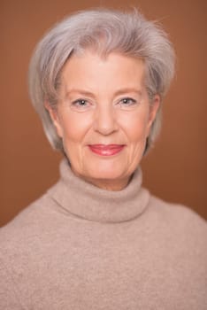 Studio recording of a smiling older woman against a brown background