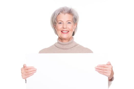 Smiling senior woman with an empty advertising sign against a white background