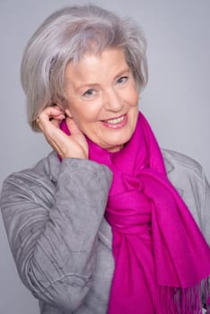 Studio recording of an active senior woman against a grey background