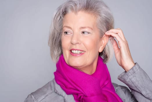 Studio recording of an active senior woman against a grey background