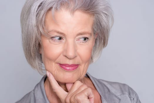 Studio recording of an active senior woman against a grey background