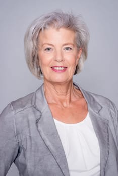Studio recording of an active senior woman against a grey background