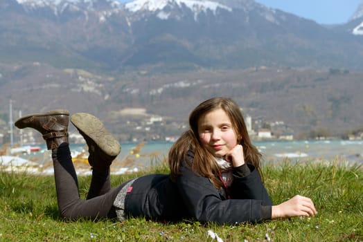 a pretty preteen is lying in the green grass, in the spring