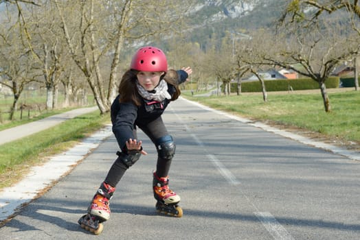 a pretty preteen girl on roller skates in helmet at a track