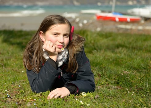 a pretty preteen is lying in the green grass, in the spring