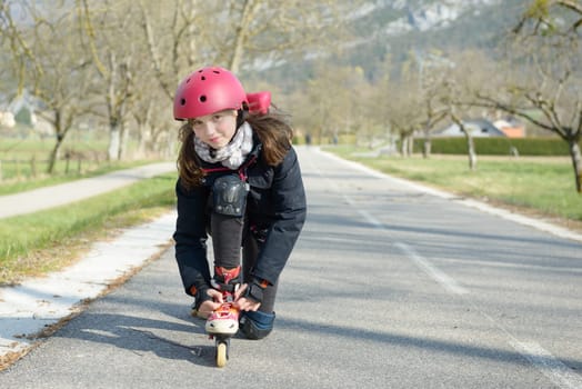 a pretty preteen girl on roller skates in helmet at a track