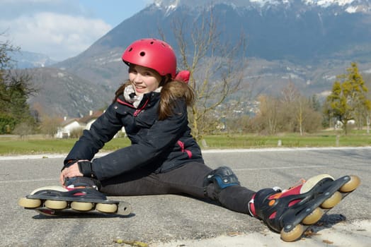 a preteen girl in rollerskate sitting on the road