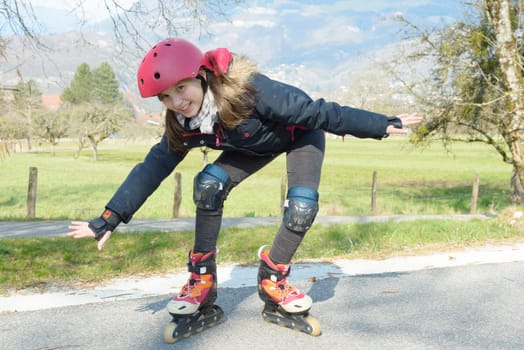 a pretty preteen girl on roller skates in helmet at a track