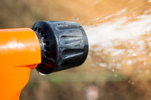 Closeup of hand held sprinkler with water spraying on the field