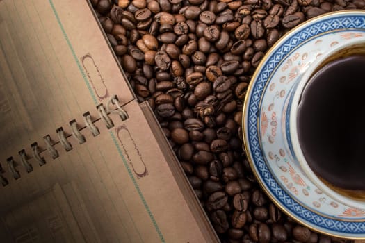 Cup of coffee and notebook on coffee background