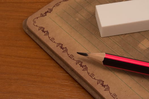 Pencil eraser and notebook on wooden table