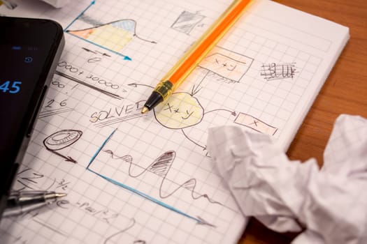 Notebook full of mathematics. Smart phone, pencils and crumpled paper are visible
