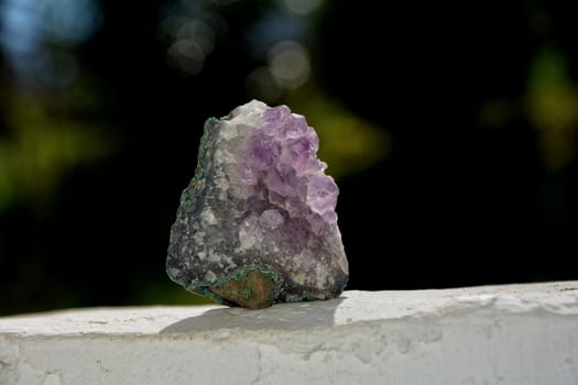 Purple amethyst on white wall against a green background