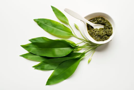 Wild garlic leafs and pesto on white background overhead shoot