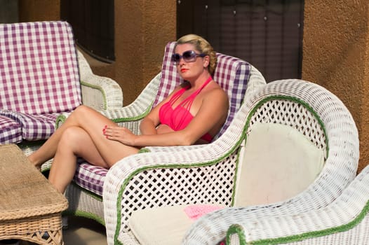 the beautiful woman in a red bathing suit sits in a chair