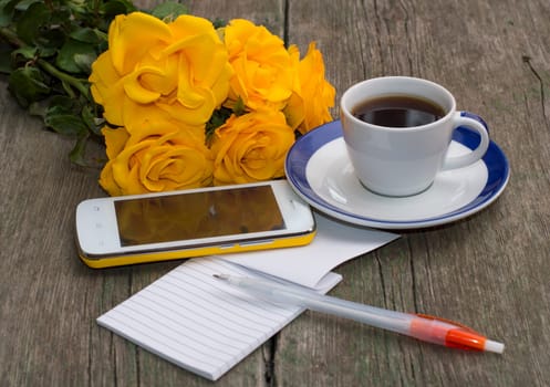 cup of coffee, phone, bouquet of roses and notebook with the handle