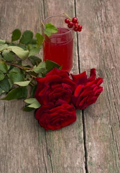 glass of juice, currant on a glass and a bouquet of red roses