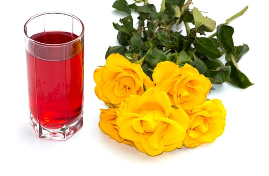 glass of juice and yellow roses on a white background