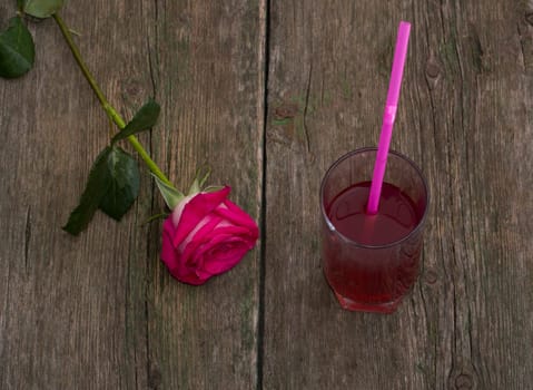 glass of juice and lonely red rose on a table