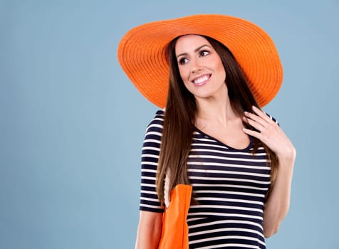 young woman wearing dress and orange hat on blue background