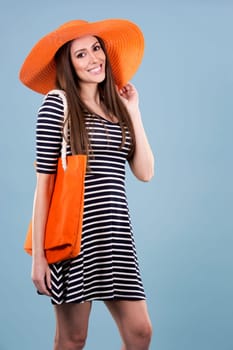 young woman wearing dress and orange hat on blue background