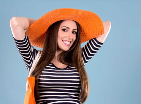 young woman wearing dress and orange hat on blue background