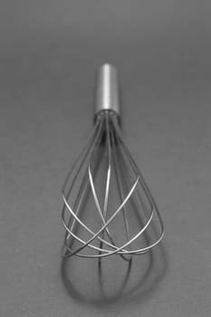 Manual hand egg beater mixer isolated on gray background